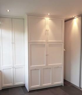 Bijkeuken met grote kastenwand op maat en witgoed achter deuren