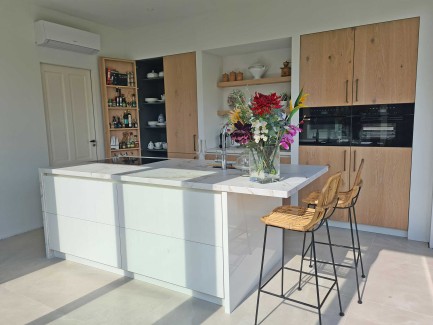 Moderne lichte eiken keuken met wit kookeiland en marmerlook kookeiland