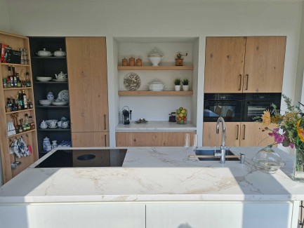 Moderne lichte eiken keuken met grote kastenwand