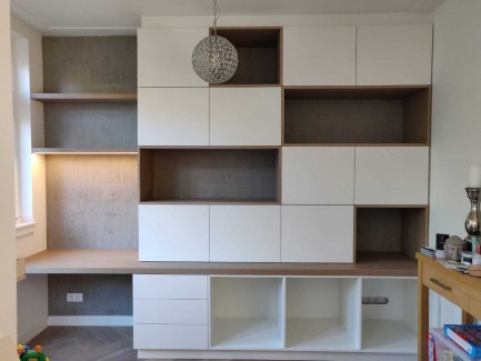 Speelse boekenkast met geïntegreerd bureau en houten kaders en witte fronten