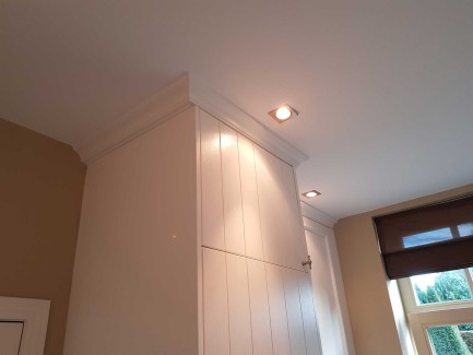 Bijkeuken met grote kastenwand op maat en witgoed achter deuren