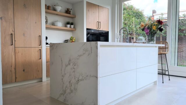 Moderne licht eiken keuken met wit kookeiland en marmer look werkblad
