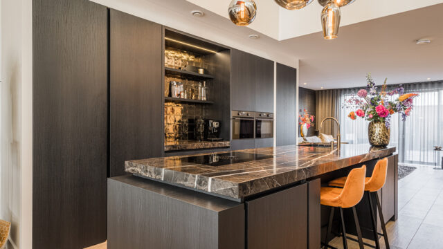 Moderne zwarte keuken met kookeiland en natuurstenen blad